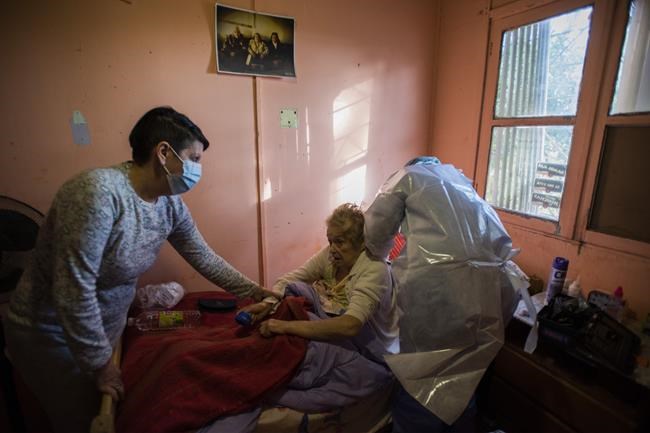Doctor Carolina Moreira, right, checks on COVID-19 patient Irma Llanes, 82, center, at her home in Montevideo, Uruguay, Monday, May 31, 2021. (AP Photo/Matilde Campodonico)