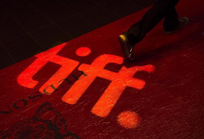 A man walks on a red carpet displaying a sign for the Toronto International Film Festival at the TIFF Bell Lightbox in Toronto on September 3, 2014. The Toronto International Film Festival kicks off today with an emphasis on the big screen and big pandemic precautions.THE CANADIAN PRESS/Darren Calabrese
