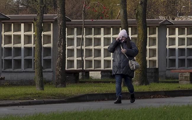 A woman wipes her face as she walks past an empty columbarium wall prepared for funerary urns holding cremated remains of the deceased, near a crematorium in St. Petersburg, Russia, Monday, Oct. 18, 2021. Russia's total number of coronavirus infections has topped 8 million and the daily infection toll hit a new record. The death toll is minutely lower than the record 1,002 tallied on Saturday, but it shows the country continuing to struggle with the virus as vaccination rates remain low. (AP Photo/Dmitri Lovetsky)