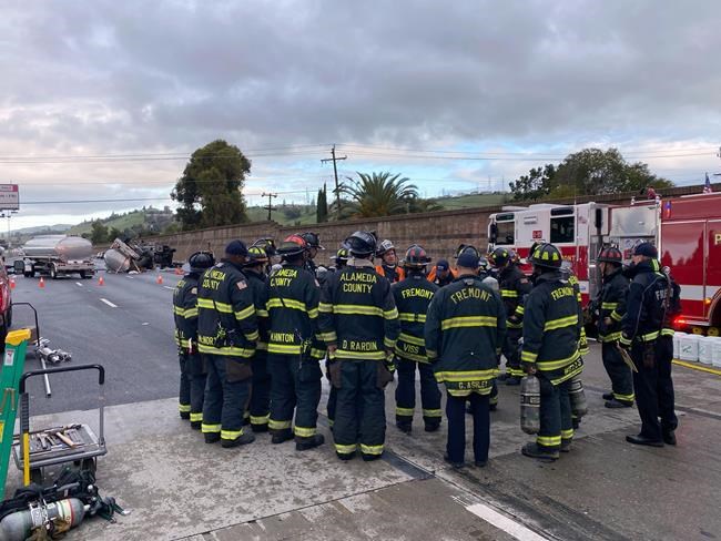 In this photo provided by the Fremont Fire Department, emergency personnel stage at the scene of a fuel tanker accident on Interstate 680, Friday, Dec. 24, 2021, in Fremont, Calif. About 100 homes have been evacuated in the San Francisco Bay Area after a fuel tanker overturned and leaked gasoline. (Aisha Knowles/Fremont Fire Department via AP)