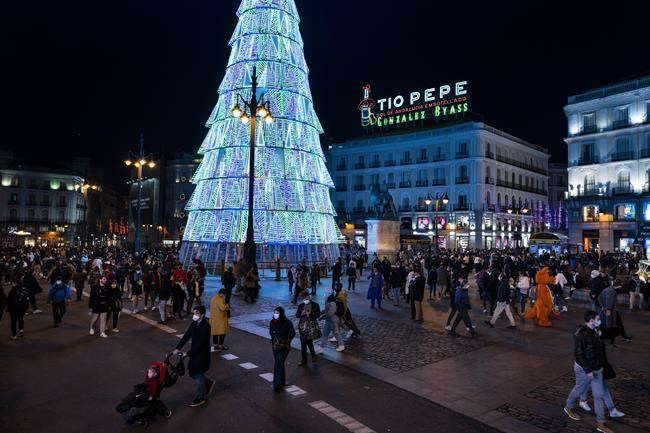 People walk along Sol square in downtown Madrid, Spain, Tuesday, Dec. 21, 2021. Despite vaccination rates that make other governments envious, Spain and Iberian neighbor Portugal are facing the hard truth that these winter holidays won't be a time of unrestrained joy. The reason is the new omicron variant that has been running rampant across Europe. (AP Photo/Bernat Armangue)