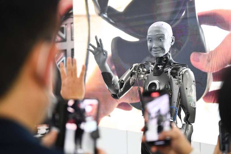 Attendees take pictures and interact with the Engineered Arts Ameca humanoid robot with artificial intelligence as it is demonst