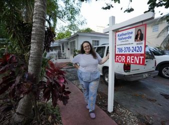 Krystal Guerra, 32, poses for a picture outside her apartment, which she has to leave after her new landlord gave her less than a month's notice that her rent would go up by 26%, Saturday, Feb. 12, 2022, in the Coral Way neighborhood of Miami. Guerra, who works in marketing while also pursuing a degree part-time, had already been spending nearly 50% of her monthly income on rent prior to the increase. Unable to afford a comparable apartment in the area as rents throughout the city have risen dramatically, Guerra is putting many of her belongings into storage and moving in with her boyfriend and his daughter for the time being. (AP Photo/Rebecca Blackwell)