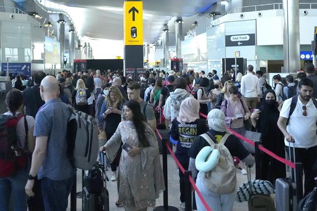 Travellers queue at security at Heathrow Airport in London, Wednesday, June 22, 2022. People face travelling disruption and long queues at airports amid the industry's ongoing staffing crisis. (AP Photo/Frank Augstein)
